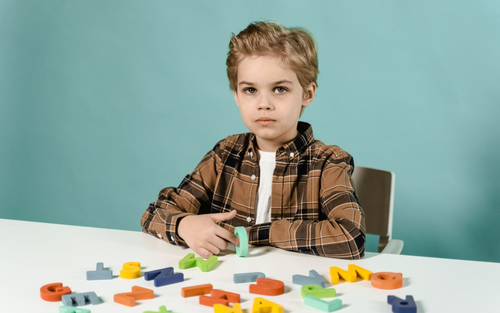 Хлопчик займається з пластикоаими літерами | © Pexels